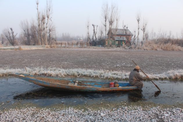 A boatman making way through partially frozen lake