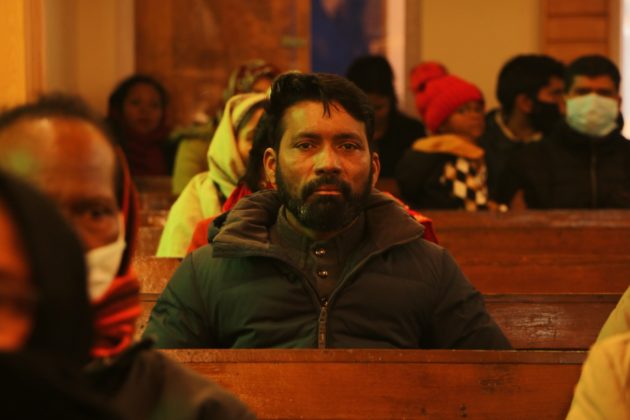 Worshipper inside the church sitting on a bench, listening to prayers.