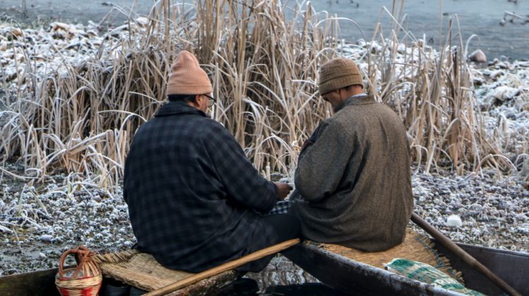On bone chilling morning two vegetable sellers exchanging money on Dal Lake.