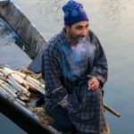 Man smoking cigarette while selling Lotus Stem 'Nadur' on his boat.