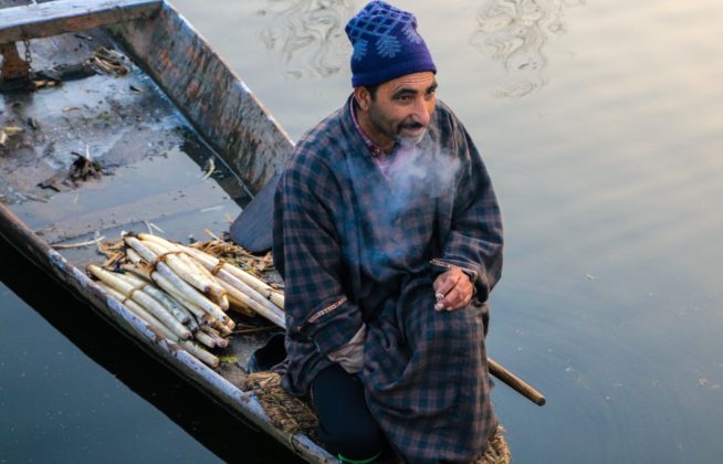 Man smoking cigarette while selling Lotus Stem 'Nadur' on his boat.