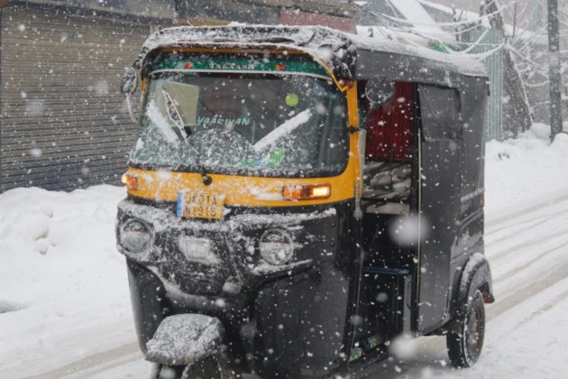 An auto rickshaw transporting through snow white roads as Kashmir receives fresh snow fall.