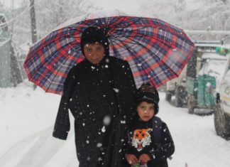 In Pictures: Life Amid Snow In Kashmir Children Under the umbrealla posing for the camera in snowfall.