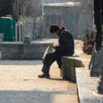 Man reading newspaper while soaking sun in the serene environment of Khanqa-E-Maula.